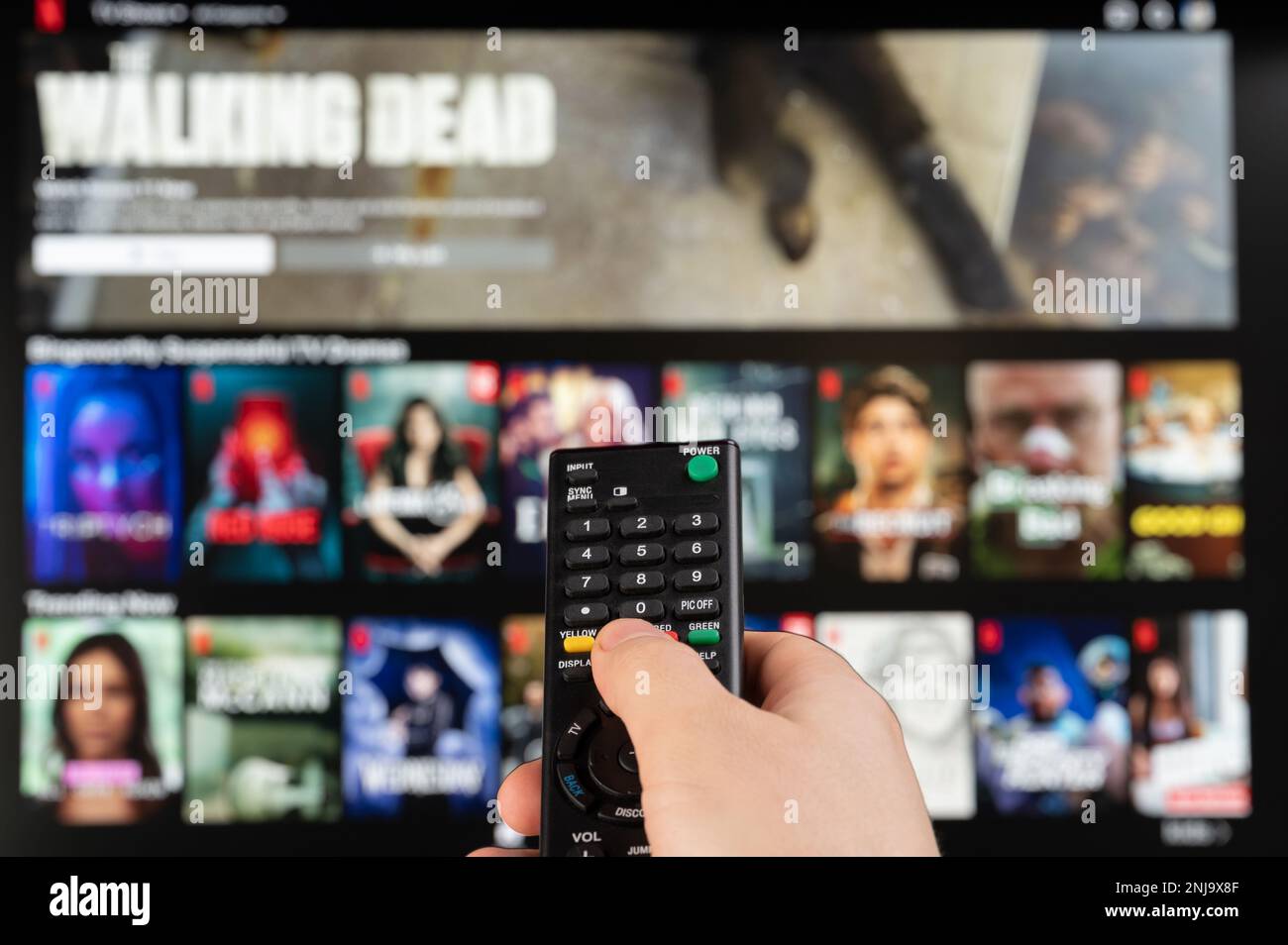 New york, USA - February 21, 2023: Select video on Netflix platform stream service on tv with remote control in hand Stock Photo