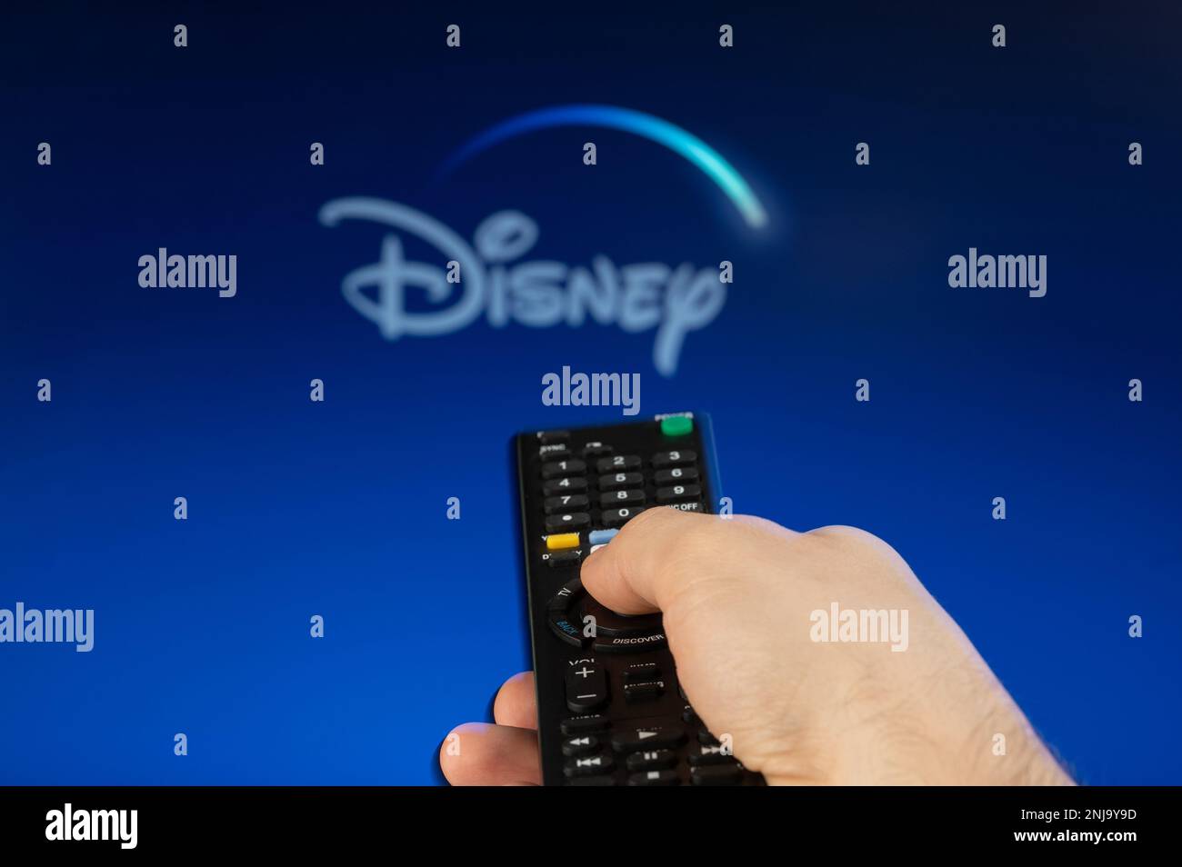 New york, USA - February 21, 2023: Play Disney streaming platform on tv with remote control in hand Stock Photo
