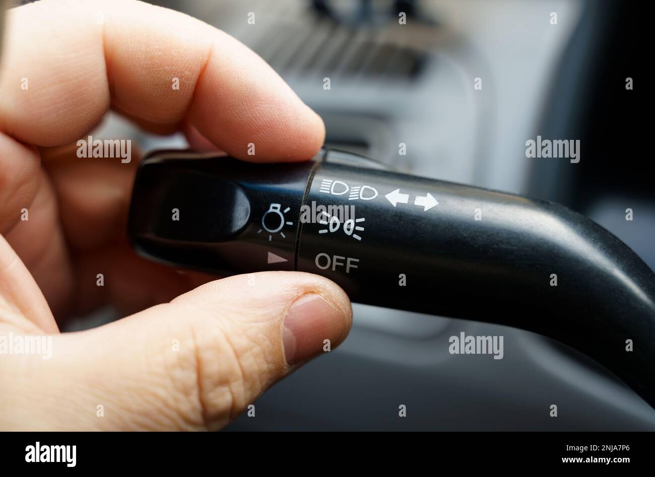 A person turns off the dipped beam and side lights of the car using the light switch. Closeup