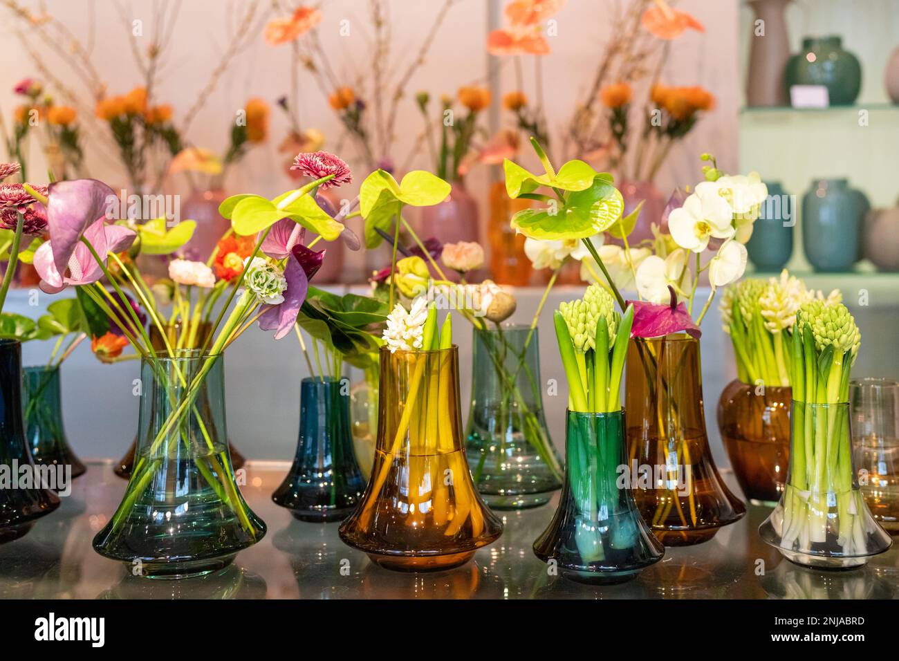 Decorative glass vases with spring flowers. Hyacinths (Hyacinthus orientalis), flamingo flowers (Anthurium) and Orchids. Stock Photo