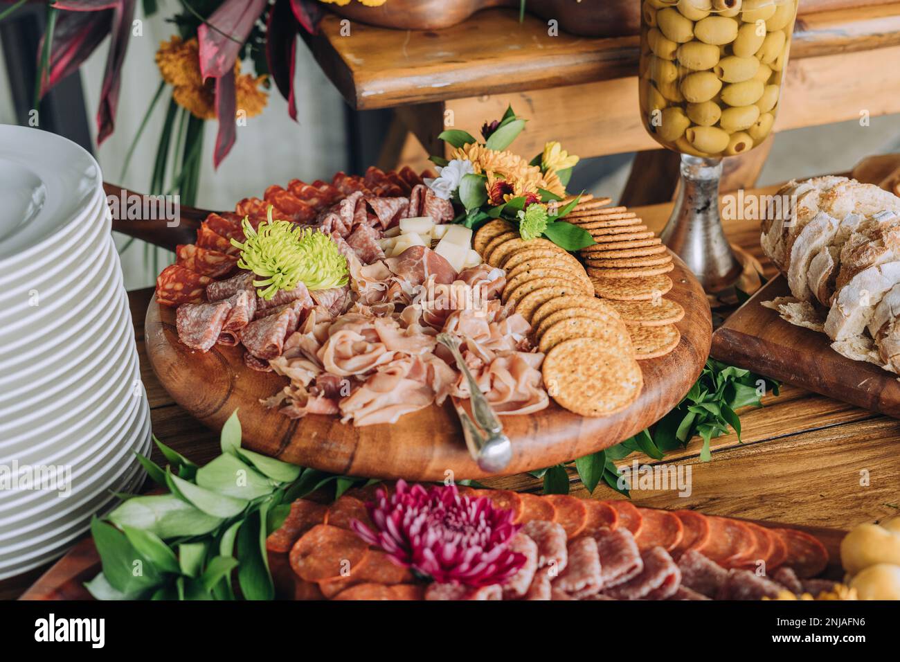An abundant selection of cured meats, crackers, and olives served on decorative platters Stock Photo