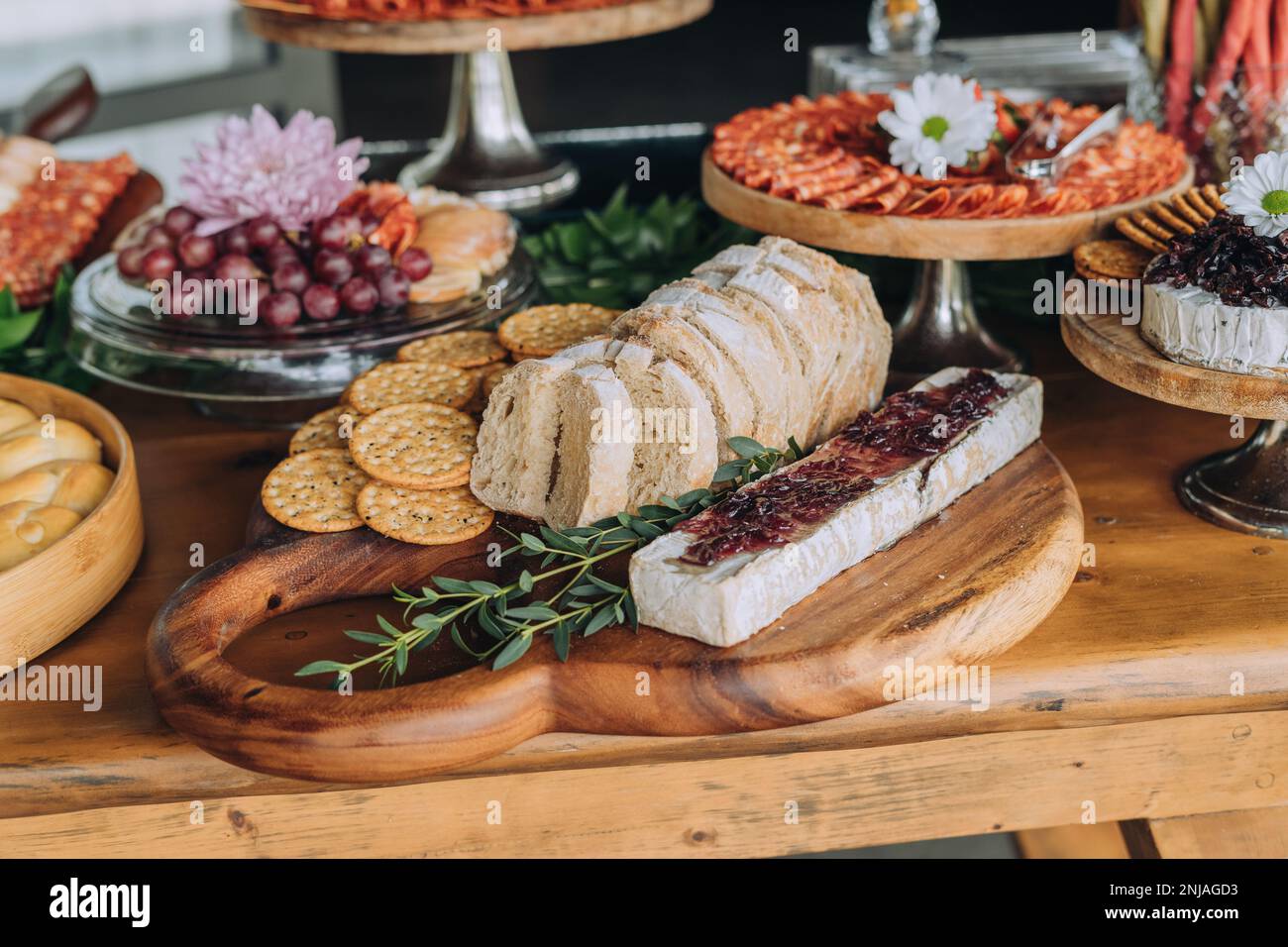 A variety of appetizers including various meats, cheese, and fruits arranged on multiple plates and platters on a wooden table Stock Photo