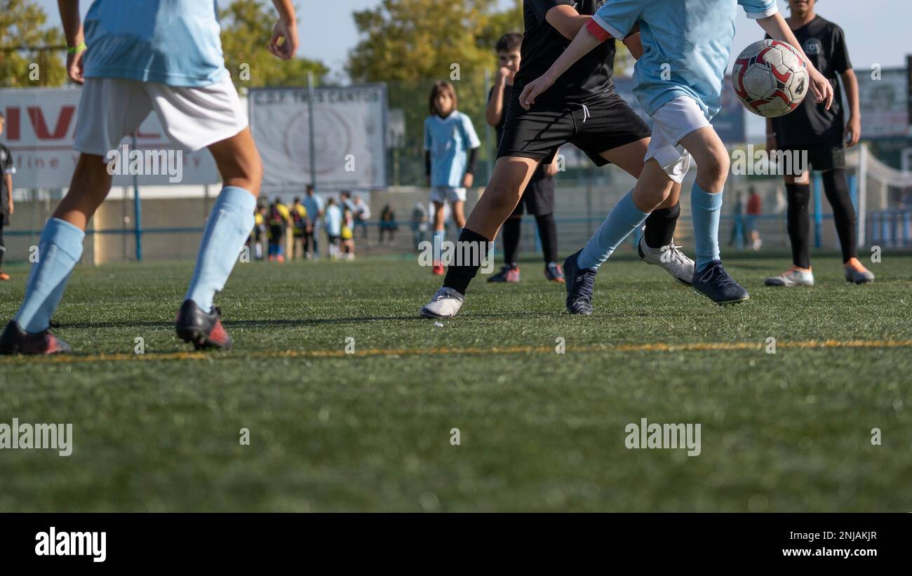 Young soccer players running fast and kicking white football ball