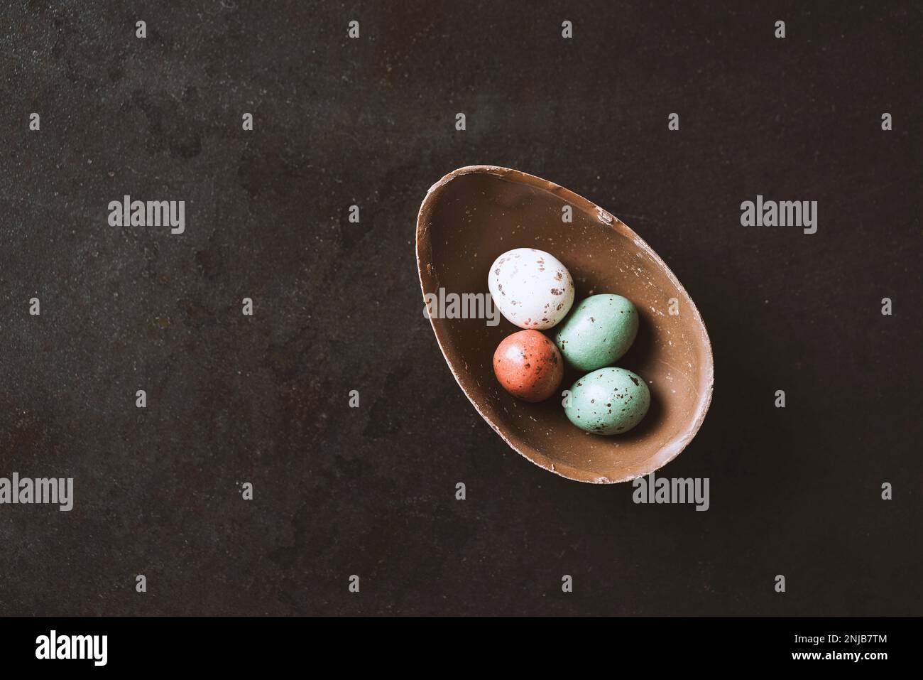 Cracked easter chocolate egg full with small chocolate eggs on black