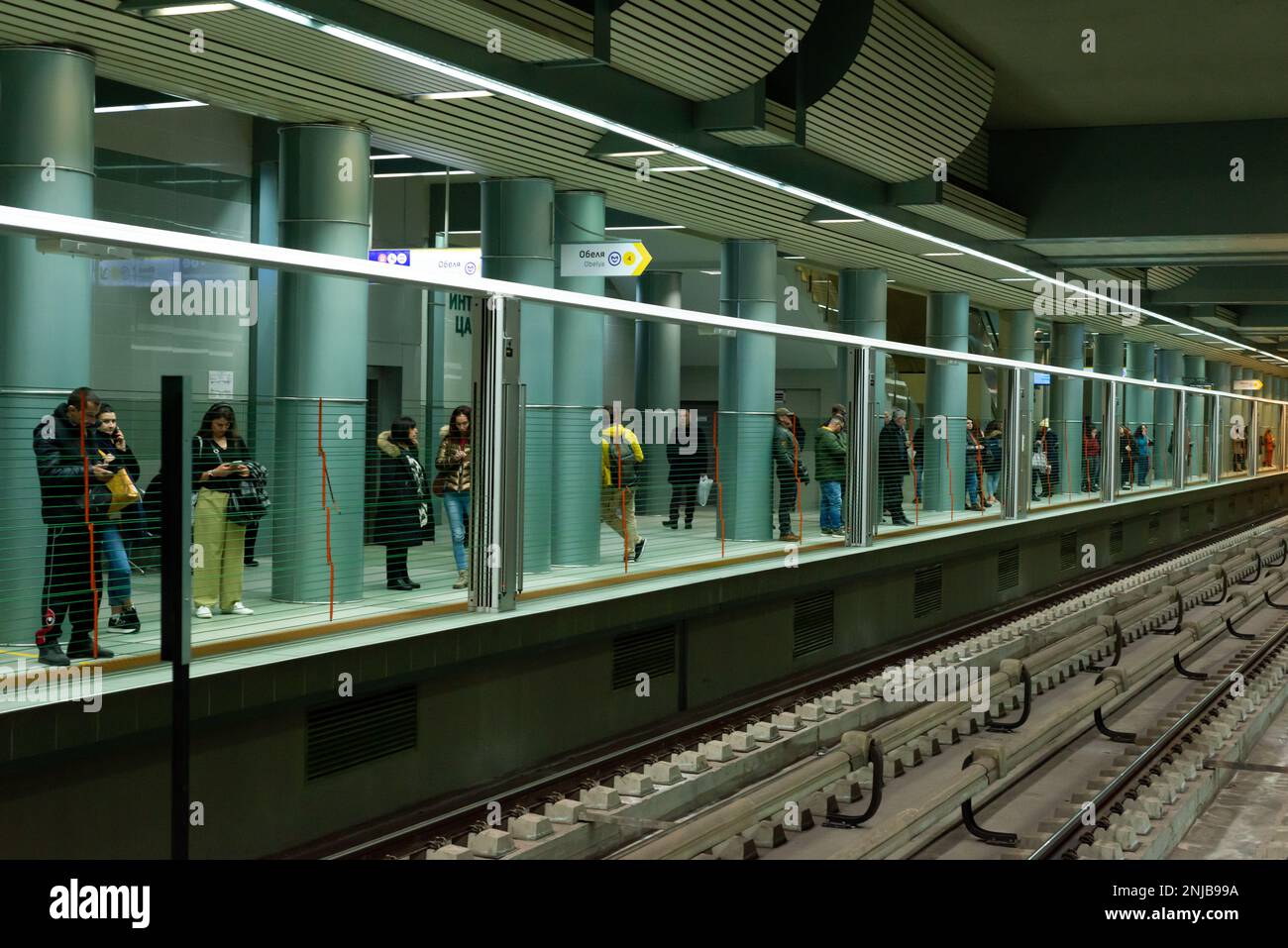 People waiting for a train behind automatic vertical platform screen barriers in underground, subway or metro station in Sofia, Bulgaria, Eastern Europe, Balkans, EU Stock Photo