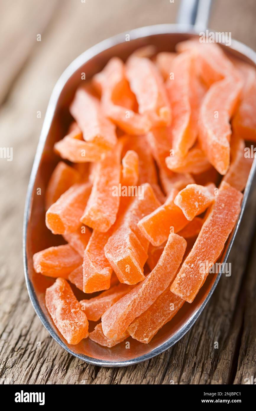 Candied or glacé papaya sticks in metal scoop on wood (Selective Focus