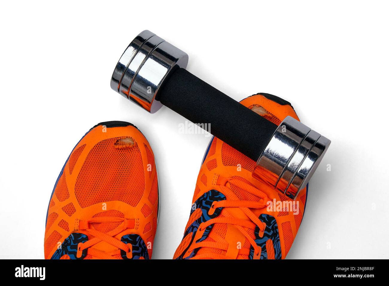 Metal heavy dumbbell fell on a leg in orange torn sneakers on a white background Stock Photo