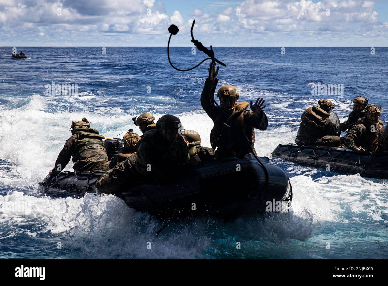 A U.S. Marine with Battalion Landing Team 2/5, 31st Marine Expeditionary Unit, throws a line during a company formation exercise off the USS New Orleans (LPD 18) in the Philippine Sea, Aug. 6, 2022. Blackhearts practiced formations on the water to refine infantry tactics. The 31st MEU is operating aboard the ships of the Tripoli Expeditionary Strike Group in the 7th fleet area of operations to enhance interoperability with allies and partners and serve as a ready response force to defend peace and stability in the Indo-Pacific Region. Stock Photo