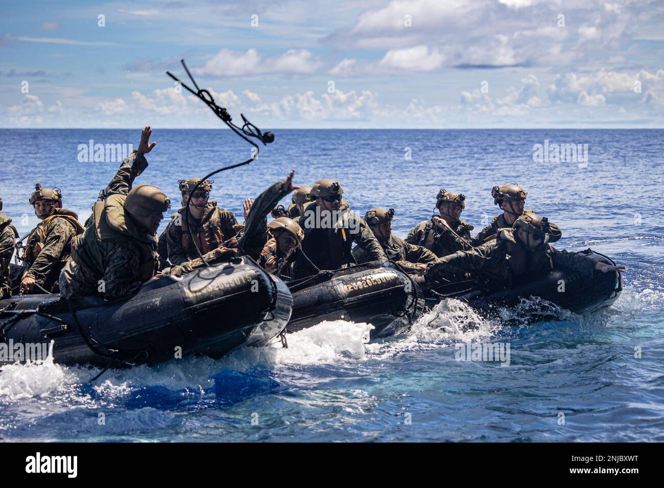 A U.S. Marine with Battalion Landing Team 2/5, 31st Marine Expeditionary Unit, throws a line during a company formation exercise off the USS New Orleans (LPD 18) in the Philippine Sea, Aug. 6, 2022. Blackhearts practiced formations on the water to refine infantry tactics. The 31st MEU is operating aboard the ships of the Tripoli Expeditionary Strike Group in the 7th fleet area of operations to enhance interoperability with allies and partners and serve as a ready response force to defend peace and stability in the Indo-Pacific Region. Stock Photo