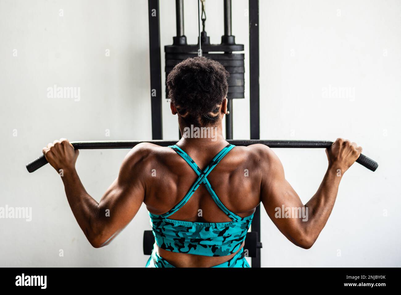 Portrait of female body fitness icon making pull ups with straight