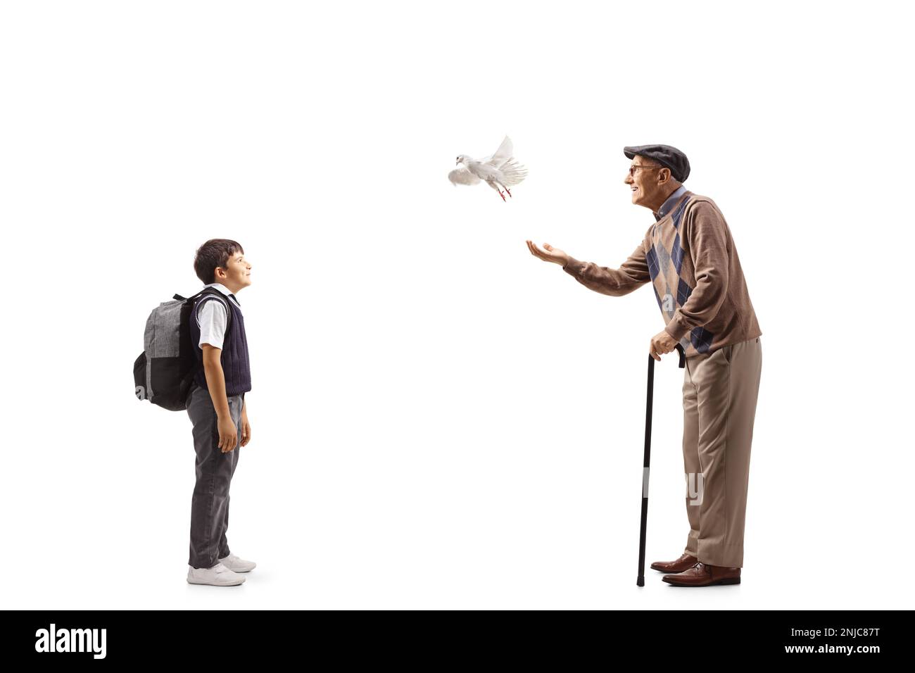 Full length profile shot of a schoolboy watching an elderly man letting a dove fly isolated on white background Stock Photo