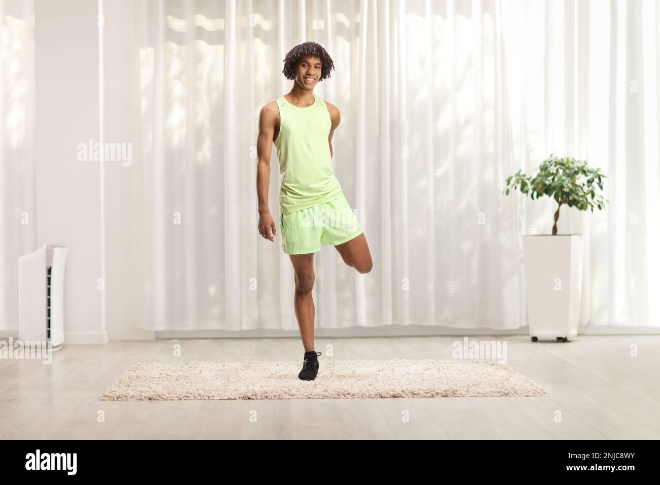 Full length portrait of an african american young man in sportswear stretching leg Stock Photo
