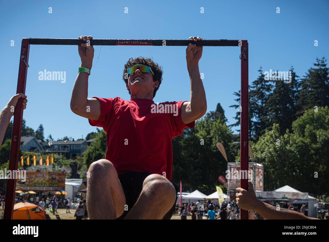 A fairgoer executes the pull-ups portion of Battle Position during the Seafair in Seattle, Washington, Aug. 5, 2022. Battle Position is the Corps' latest recruiting tool that incorporates virtual reality and challenges participants to earn the highest aggregate score of 3 events: pull-ups, ammo can lifts, and the pugil stick battle. Stock Photo