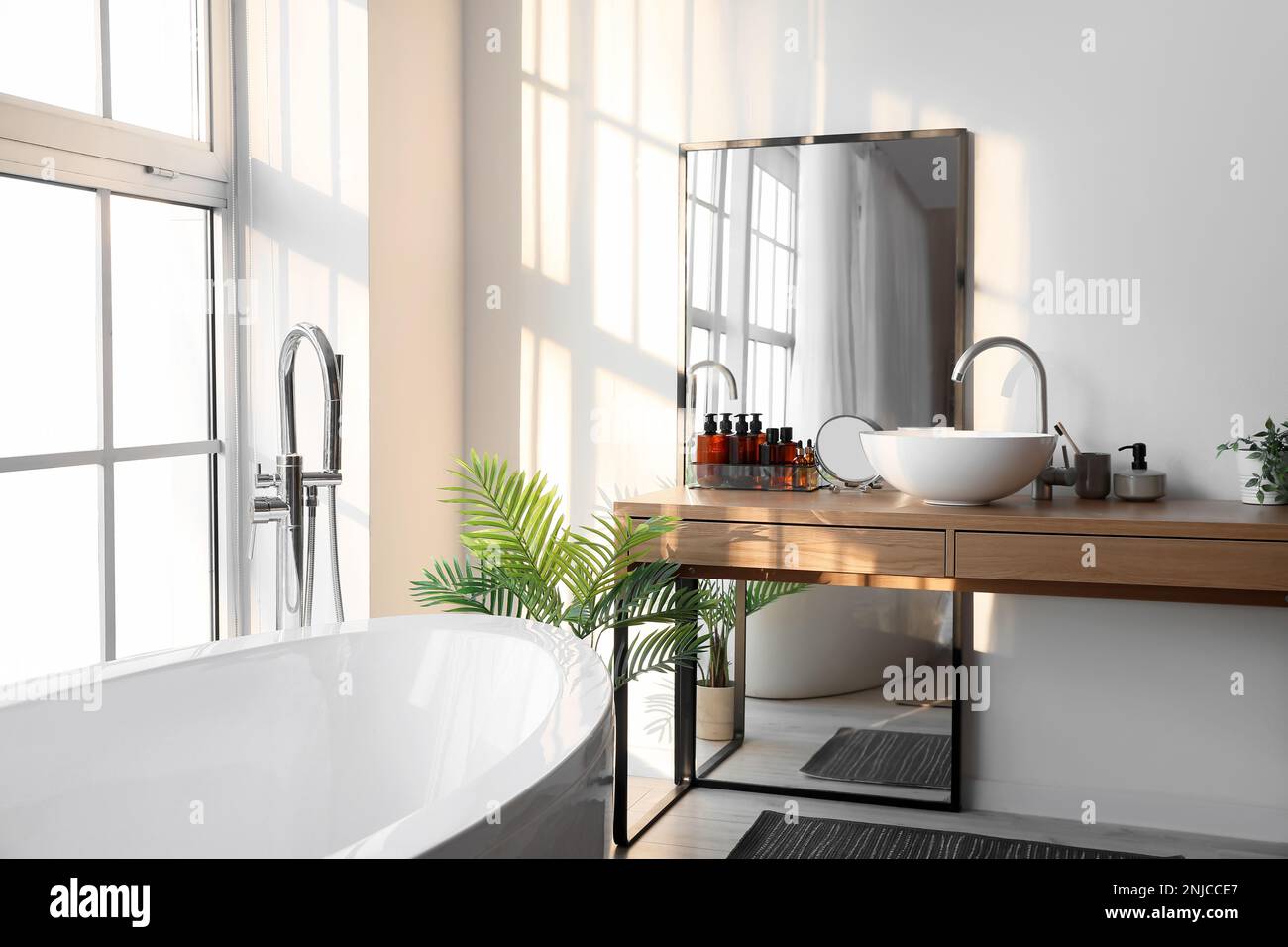 Interior of light bathroom with bathtub, table and mirror Stock Photo