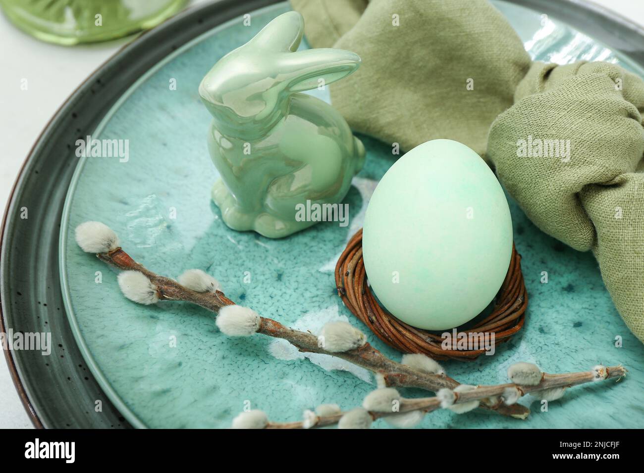 Stylish table setting with Easter egg, willow branches and ceramic bunny, closeup Stock Photo