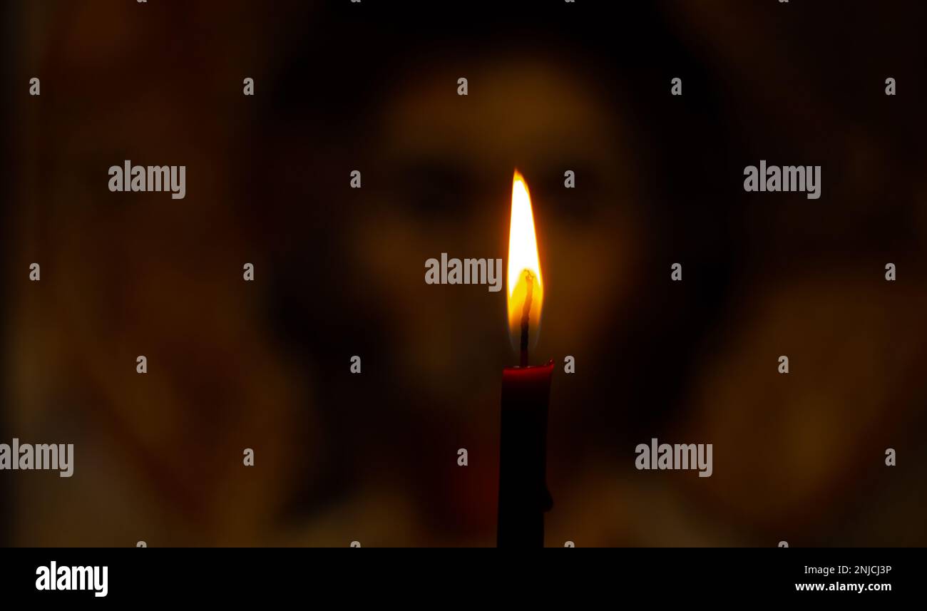 burning candle illuminates the icon of Jesus Christ Stock Photo Alamy