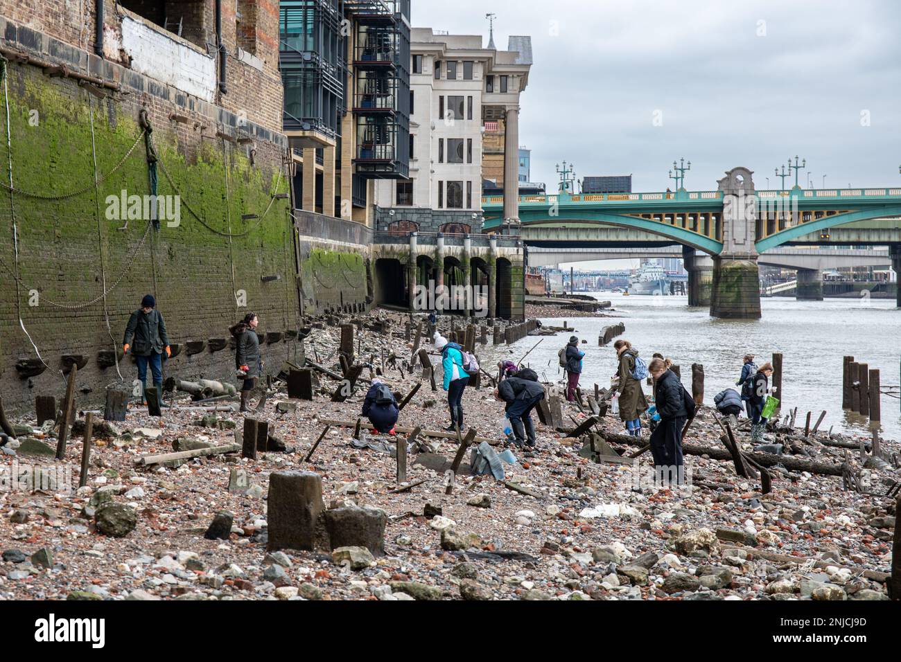 Mudlarkers mudlarking on the rocky foreshore of River Thames at low tide in London, England Stock Photo