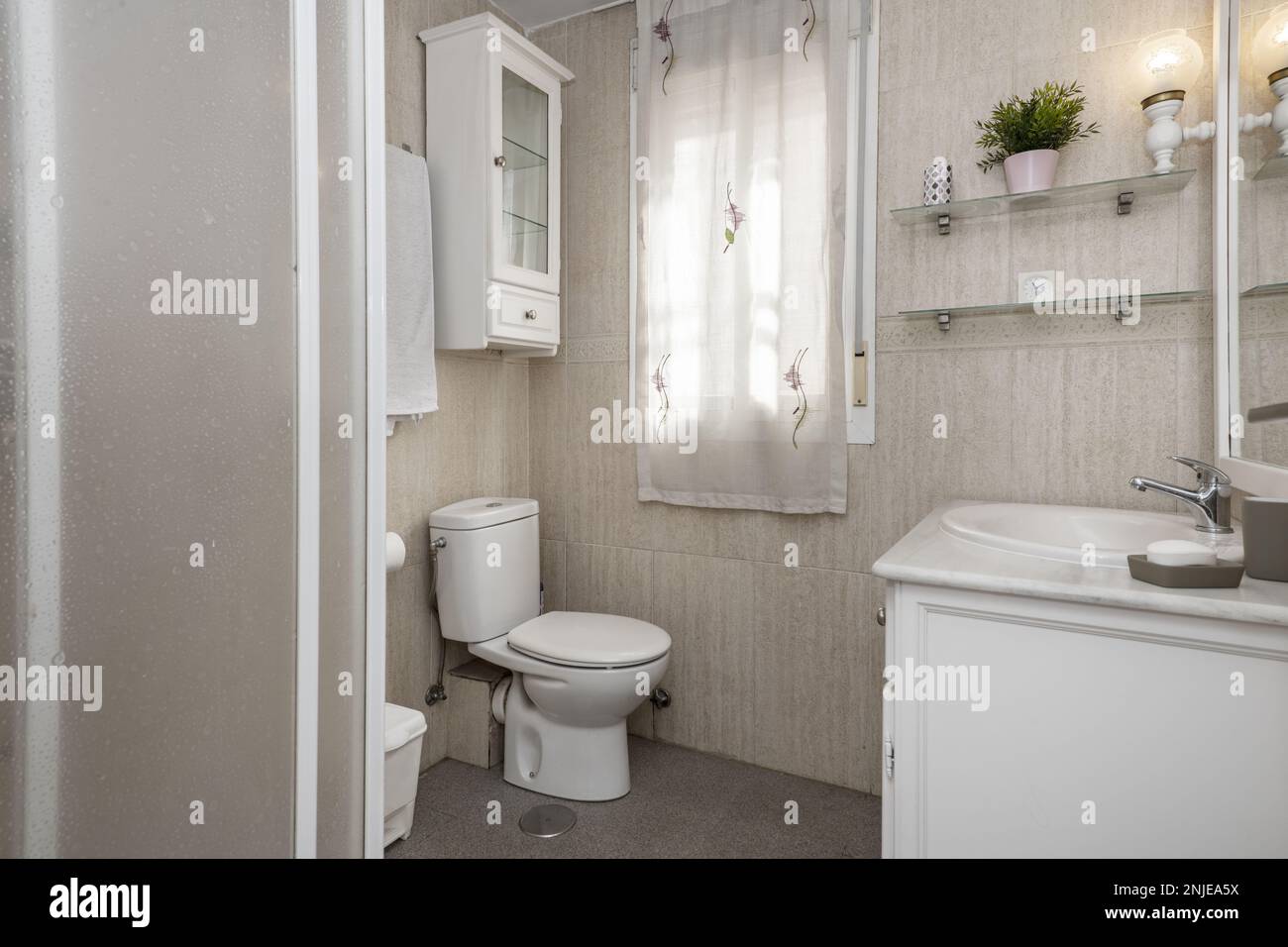 Bathroom with shower with sliding door screen, creamcolored tiles on