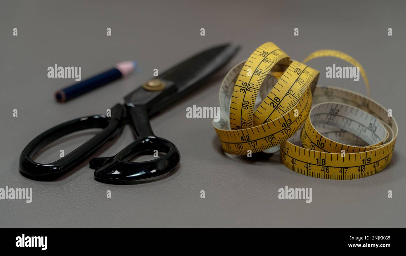 Measuring tape with a pencil on a gray background. Stock Photo