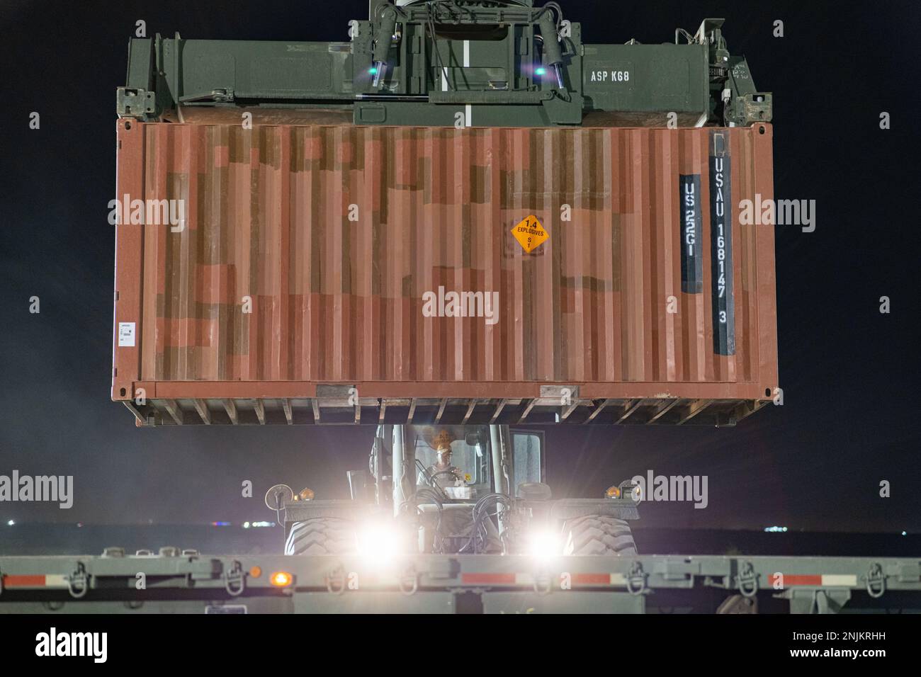 A U.S. Army Soldier operates a rough-terrain container handler to load containers on top of a M978 trailer transported by motor transport operators with the 1113th Transportation Company, Task Force Red Ball, prior to a convoy to and from the Port of Shuaiba, Kuwait, Feb. 18, 2023. The 369th Sustainment Brigade’s ammunition specialists ensured these transport operators were ready to move almost 200 containers of ammunition to support troops in combat to fight and win tonight. (U.S. Army National Guard photo by Staff Sgt. Sebastian Rothwyn) Stock Photo