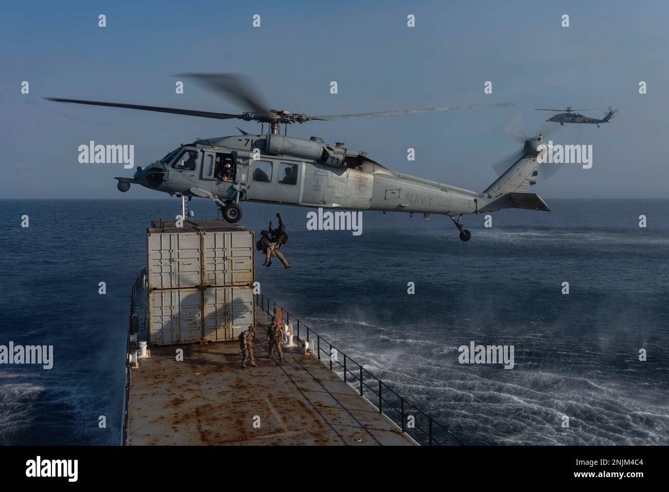 PACIFIC OCEAN (Sept. 7, 2022) U.S. Coast Guardsmen from Maritime Security Response Team West (MSRT-W) board an MH-60S Sea Hawk assigned to the “Wildcards” of Helicopter Sea Combat Squadron (HSC) 23, onto a target vessel during the Helicopter Sea Combat Weapons School Pacific (HSCWSP) quarterly exercise PHOENIX TRIDENT ASSAULT, a Helicopter Visit, Board, Search and Seizure (HVBSS) training exercise, off the coast of San Diego. Stock Photo