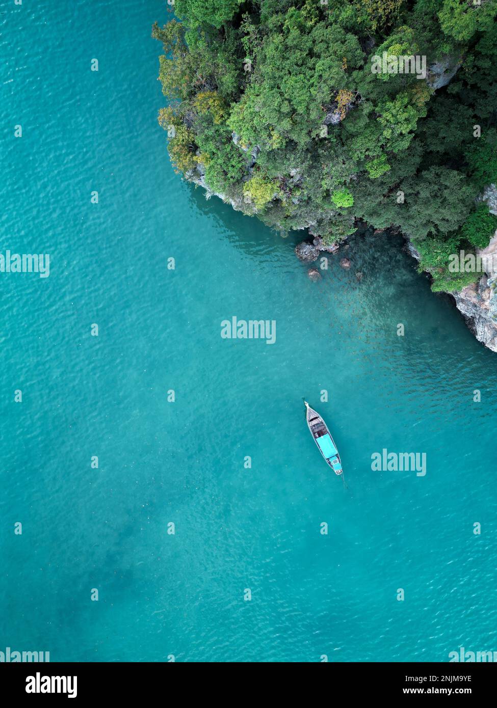 Topdown drone shot of a longtail boat in the sea near a cliff in Krabi, Thailand Stock Photo