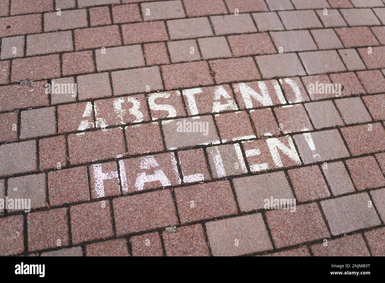 Writing on the sidewalk of a small German town during the Corona Pandemic with the words Abstand halten. Translation: keep your distance Stock Photo