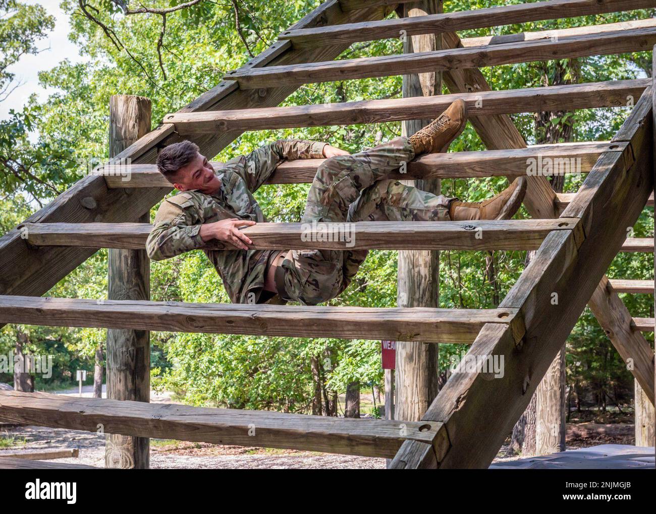 Pfc. Brayden D. Cooper, an Army Explosive Ordnance Disposal technician from the 763rd Ordnance Company (EOD), pulls up between the wooden planks that up station three – called “The Weaver” – of Fort Leonard Wood’s Confidence Course, July 1, at Training Area 97.  Cooper was training for the U.S. Army Air Assault School.  U.S. Army photo by Angi Betran, Fort Leonard Wood Public Affairs Office. Stock Photo