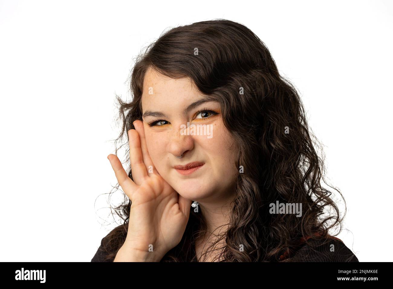 Young woman looking at camera while scrunching her nose, on white background Stock Photo