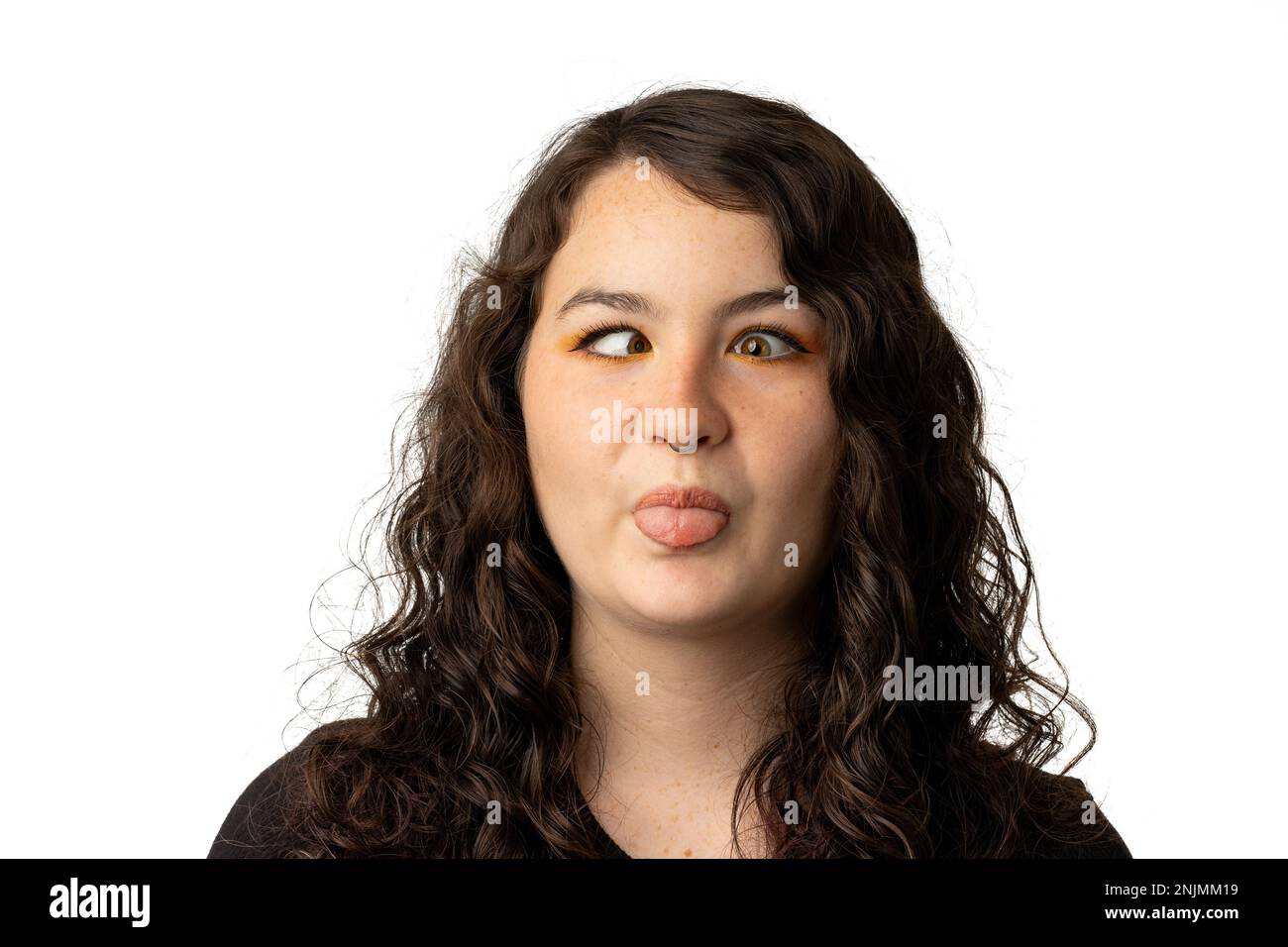 Young woman making a goofy face  and sticking out tongue, isolated on white background. Stock Photo