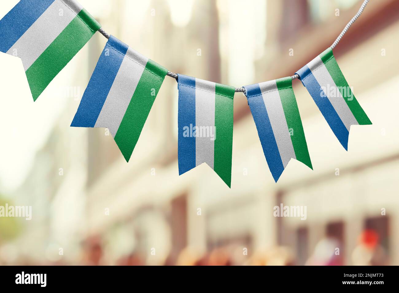 A garland of Sierra Leone national flags on an abstract blurred ...