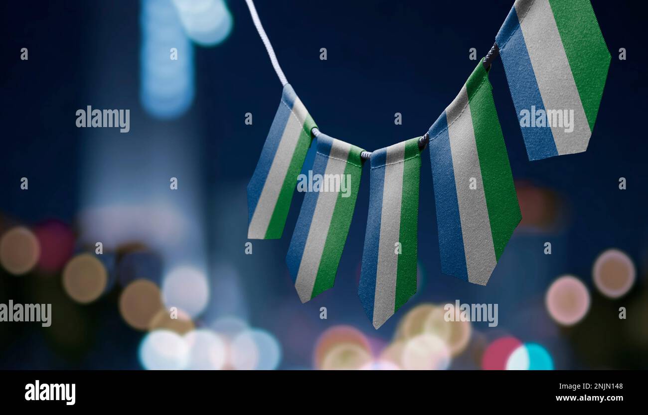 A garland of Sierra Leone national flags on an abstract blurred ...