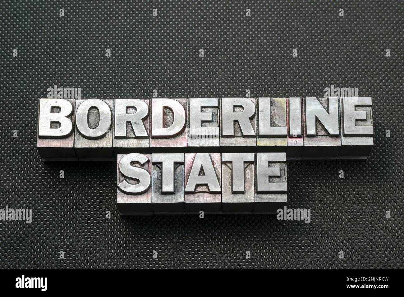 borderline state phrase made from metallic letterpress blocks on black perforated surface Stock Photo