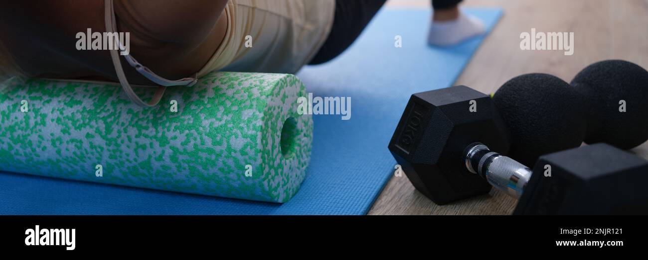 Closeup of woman riding cork massage roller to relieve tension in back