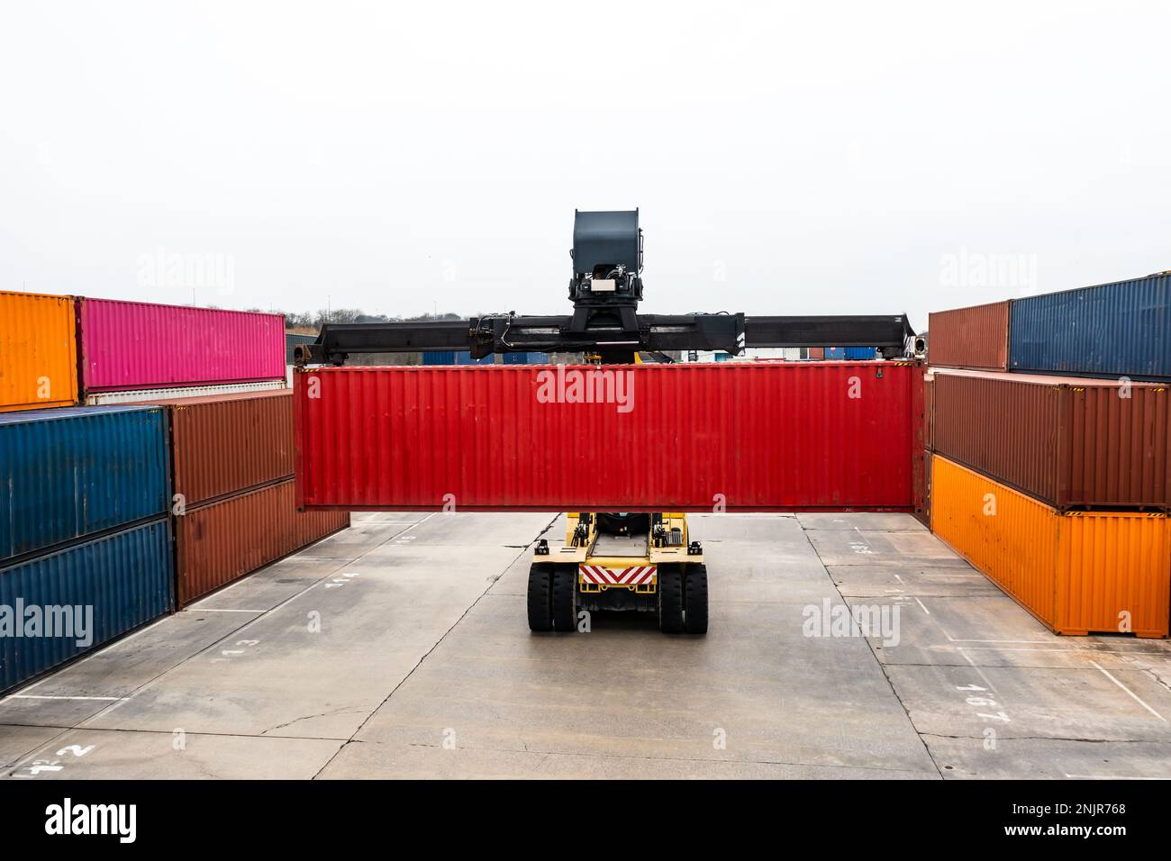 Shipping transportation background of a heavy lifting machine moving shipping containers around a commercial dock for onward movement by rail or road Stock Photo