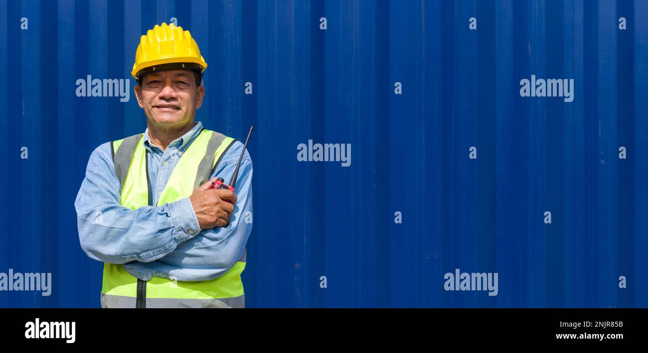 Contractor Yellow Senior contractor in safety vest and yellow hardhat holding walkie ...