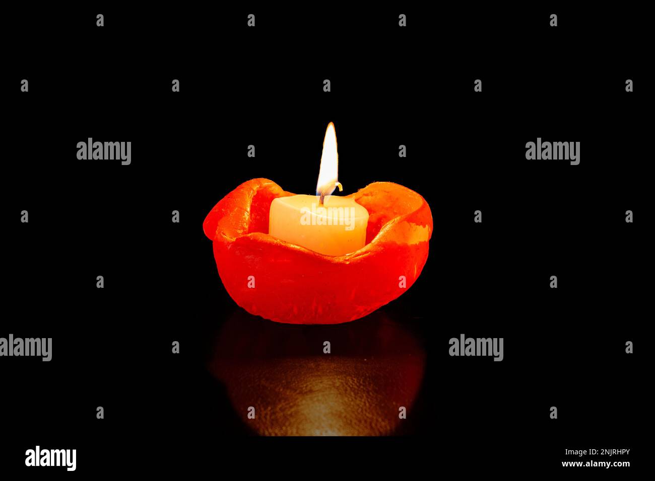 Bright burning candle with flame on black background, melted Wax, copy