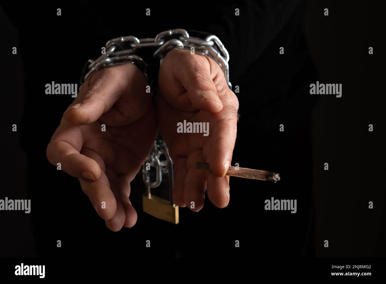 man chained to cigarette man's hands chained, with a cigarette in his fingers black background,  addiction concept Stock Photo