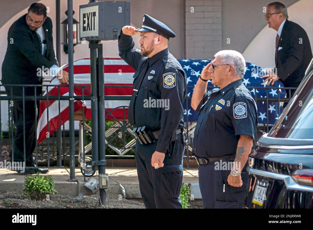 Oakdale Police Chief Jim Lauria, right, and another Oakdale police officer stand and salute as