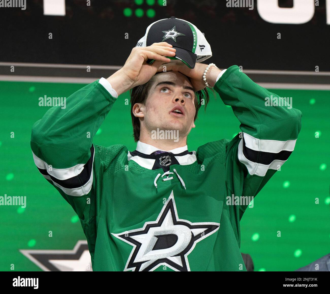 The Dallas Stars' 18th pick, Lian Bichsel, puts on his cap during