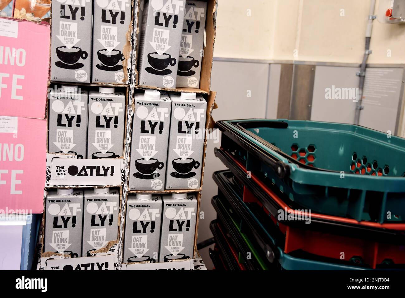 Oatly vegan oat drink Barista Edition in glass with carton behind and oats  strewn around on black background. Editorial use only Stock Photo - Alamy