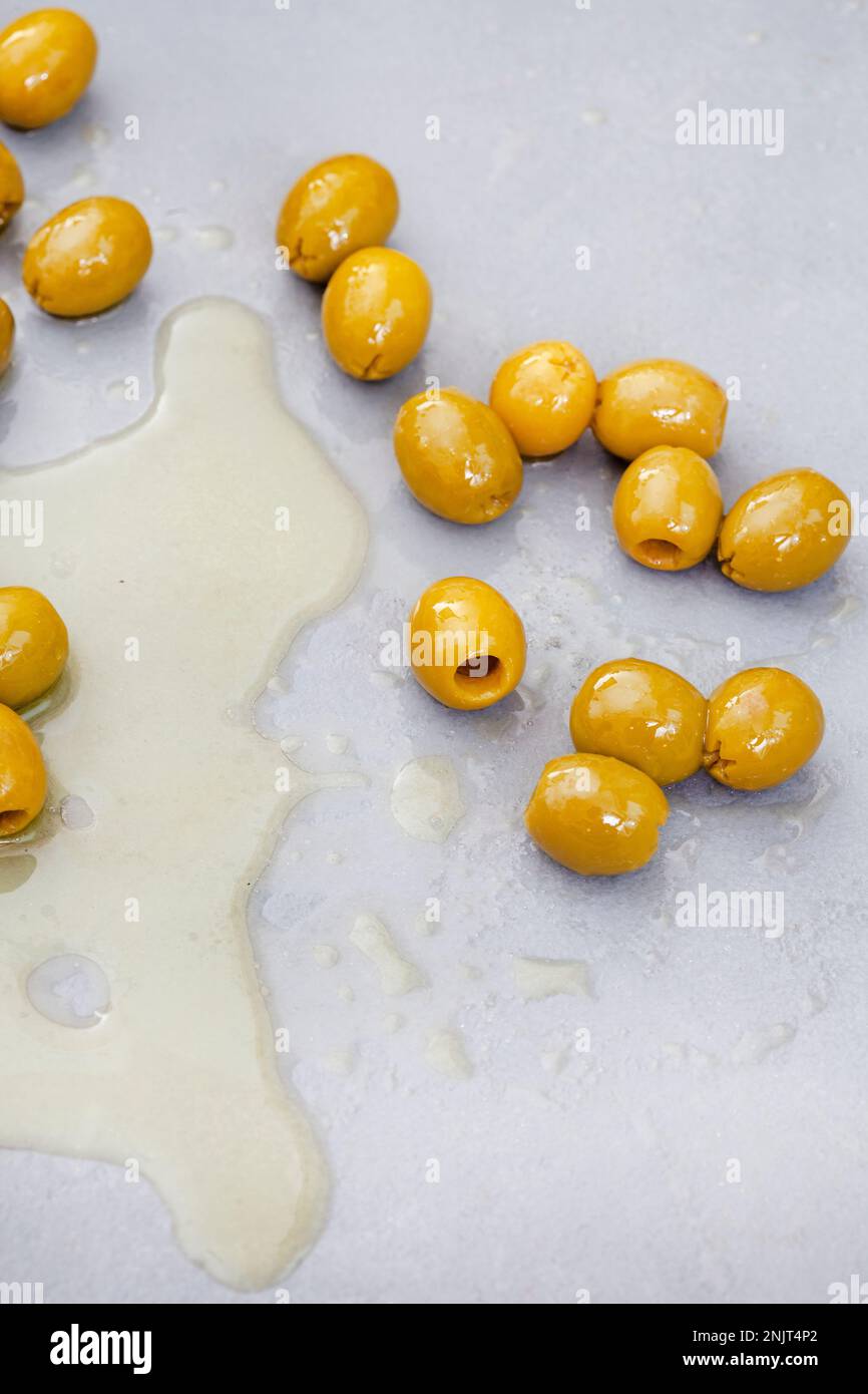 pitted green olives with oil on mottled gray with copy space Stock