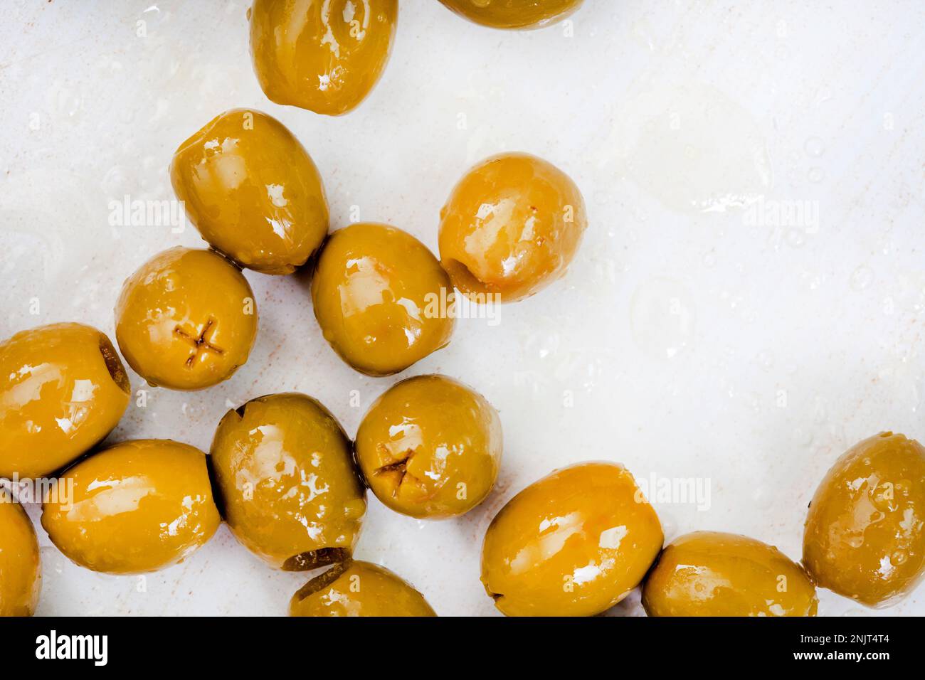 pitted green olives with oil on mottled gray with copy space Stock