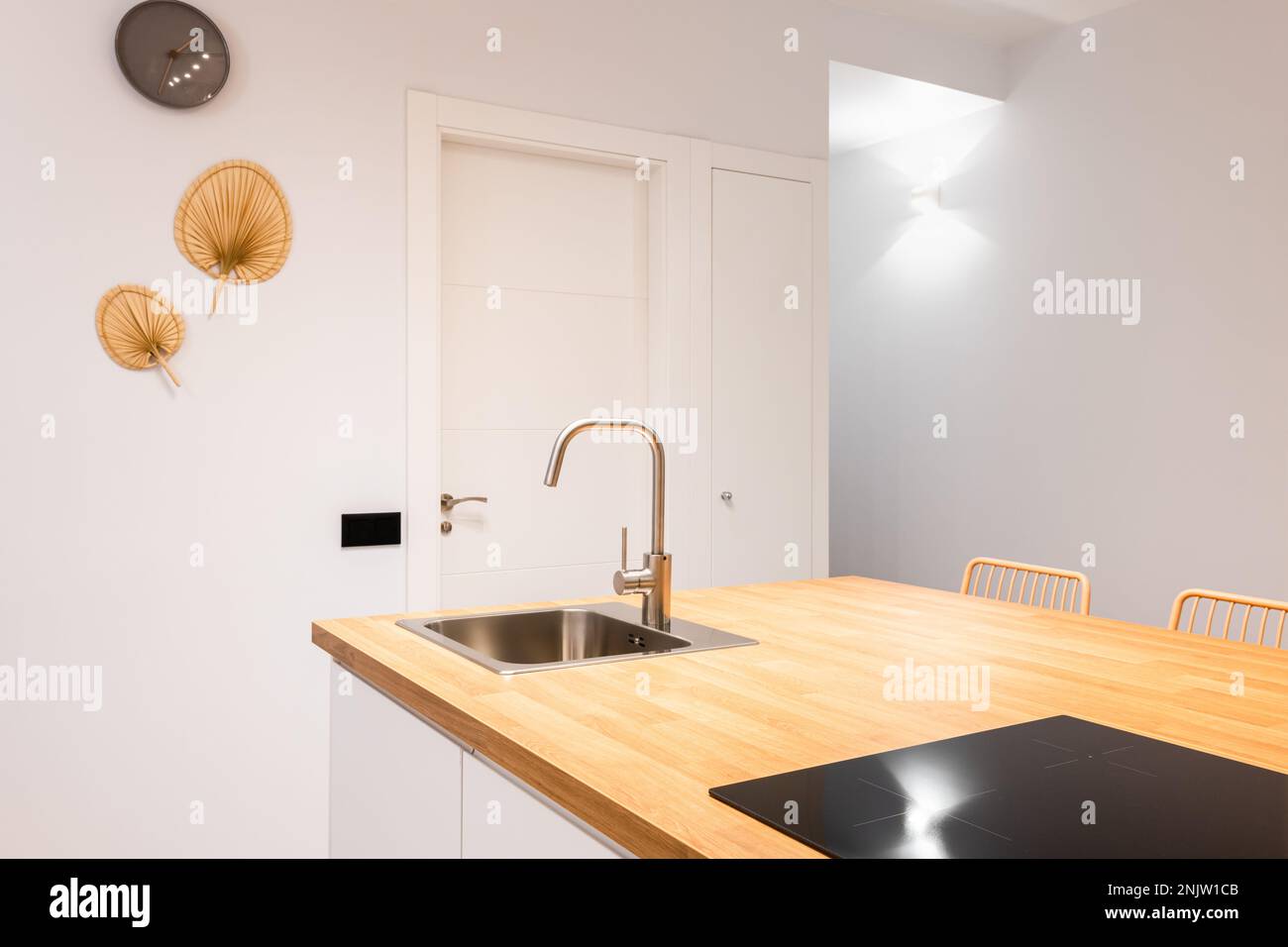 https://c8.alamy.com/comp/2NJW1CB/closeup-of-kitchen-island-wooden-table-top-in-single-honey-color-palette-countertop-has-built-in-sink-and-ceramic-plate-above-which-exhaust-system-2NJW1CB.jpg