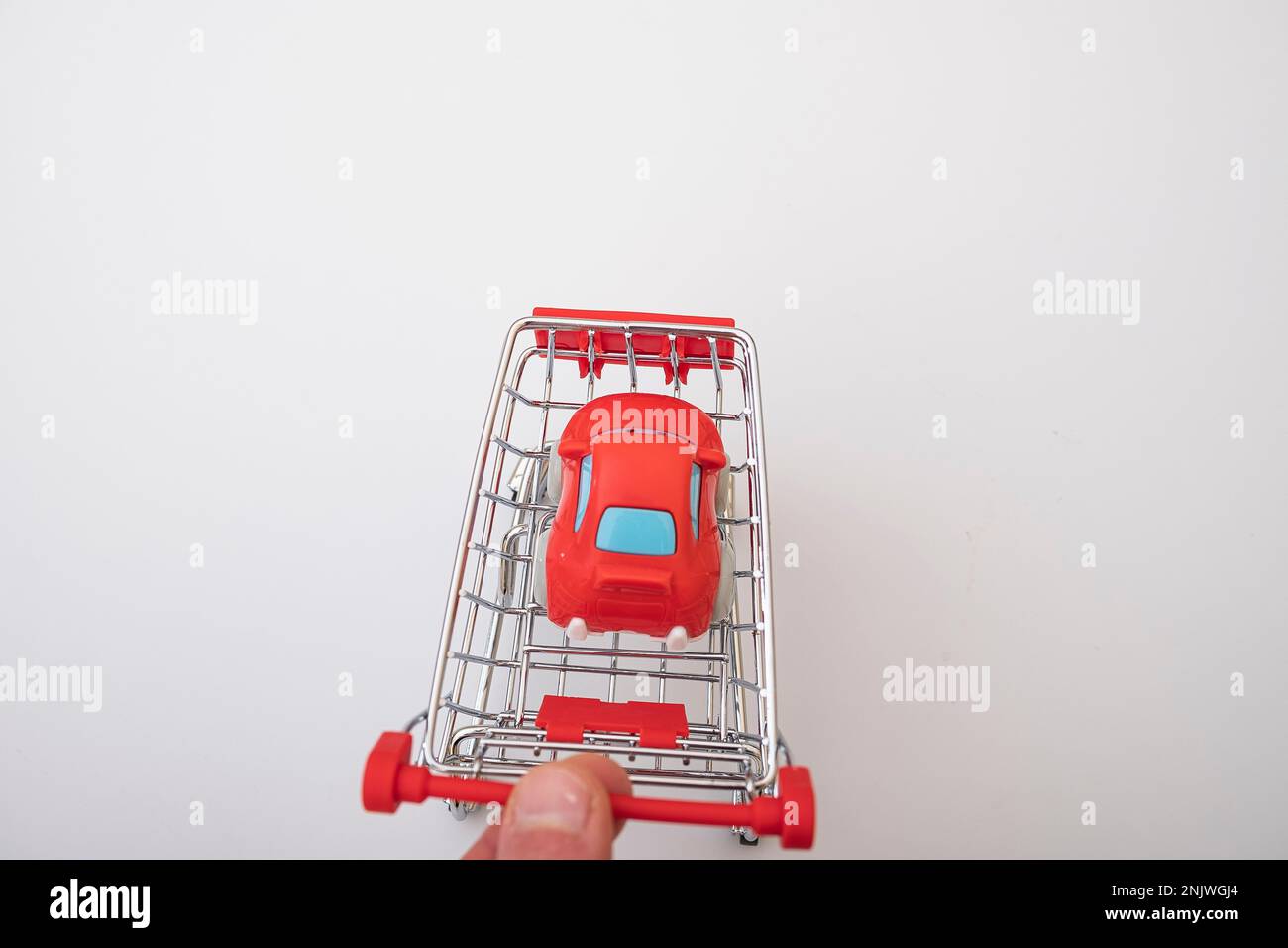 Red car in a shopping cart, isolated on white. car buying concept Stock Photo
