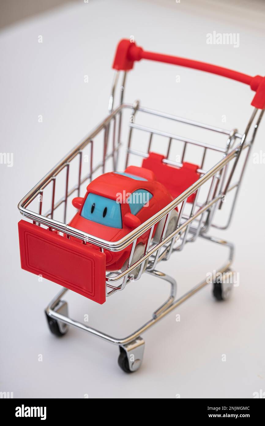 Red car in a shopping cart, isolated on white. car buying concept Stock Photo
