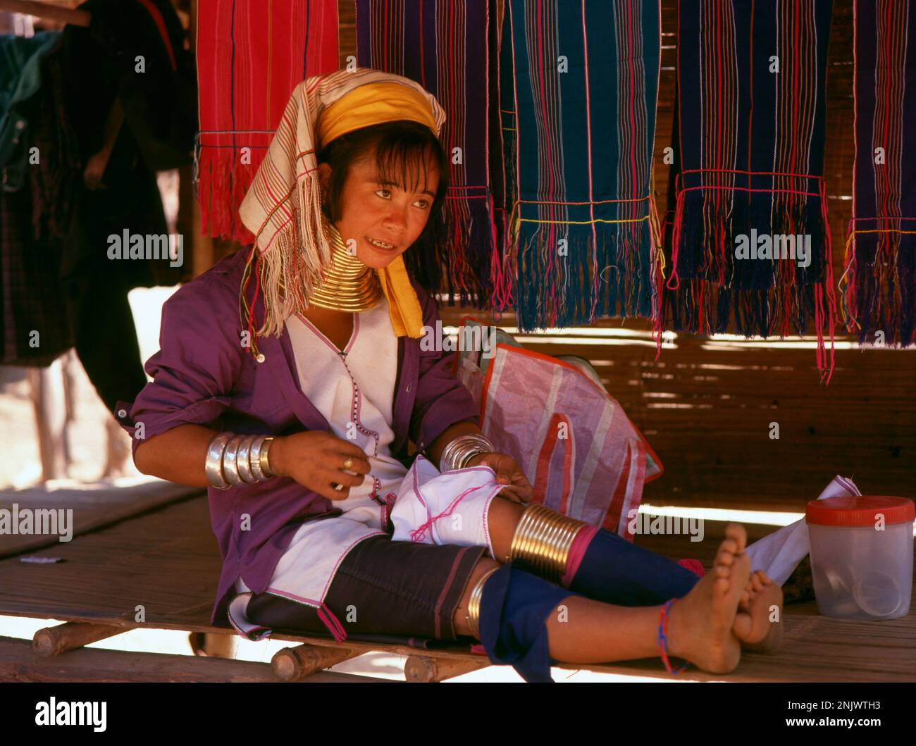 Thailand: A Padaung (Long Neck Karen) woman embroidering cloth in a village near Mae Hong Son. The Padaung or Kayan Lahwi or Long Necked Karen are a subgroup of the Kayan, a mix of Lawi, Kayan and several other tribes. Kayan are a subgroup of the Red Karen (Karenni) people, a Tibeto-Burman ethnic minority of Burma (Myanmar). Stock Photo
