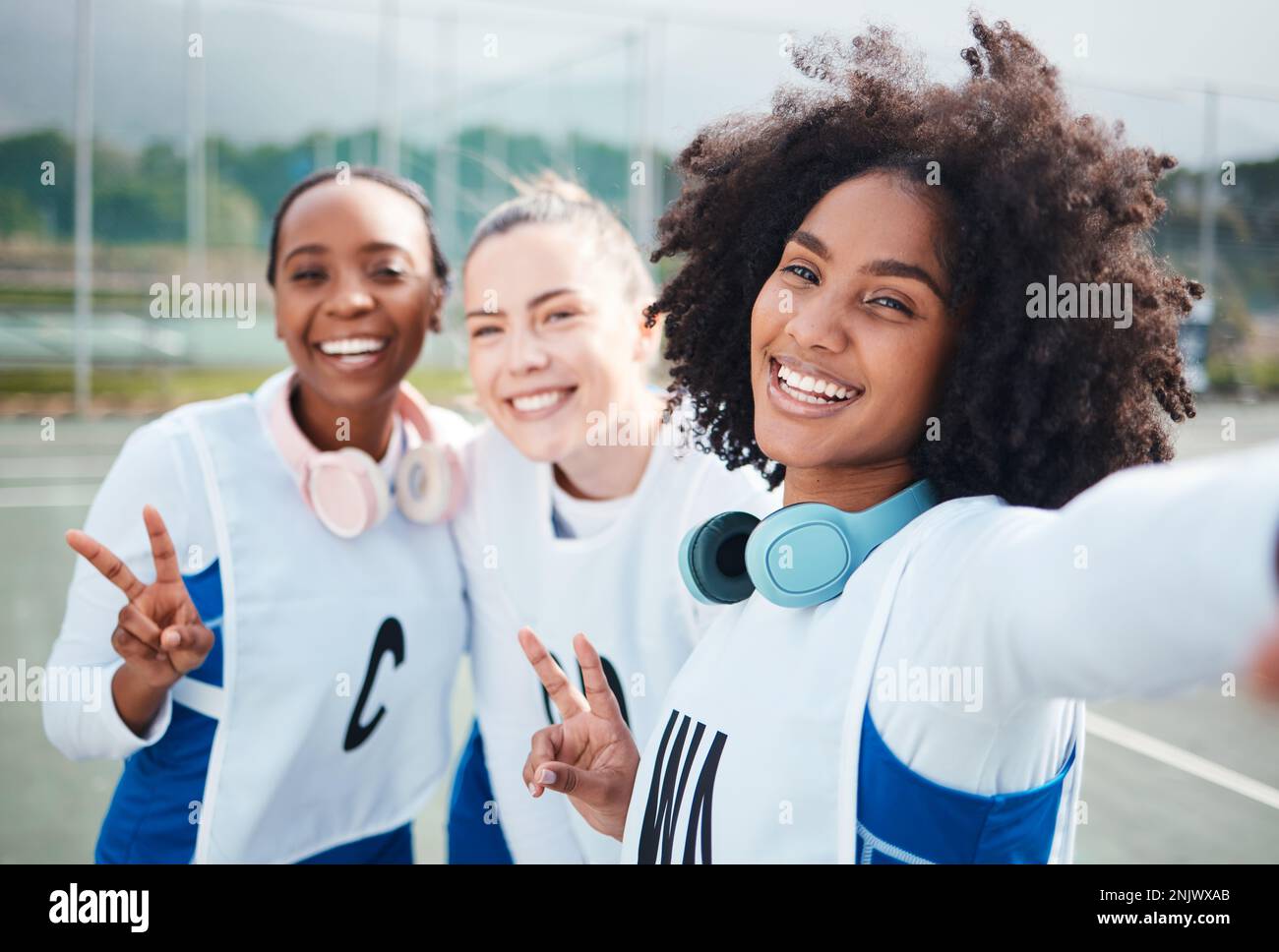 Friends, selfie and women in portrait, netball and sports with team on court outdoor, smile and peace hand sign. Diversity, headphones and gen z with Stock Photo