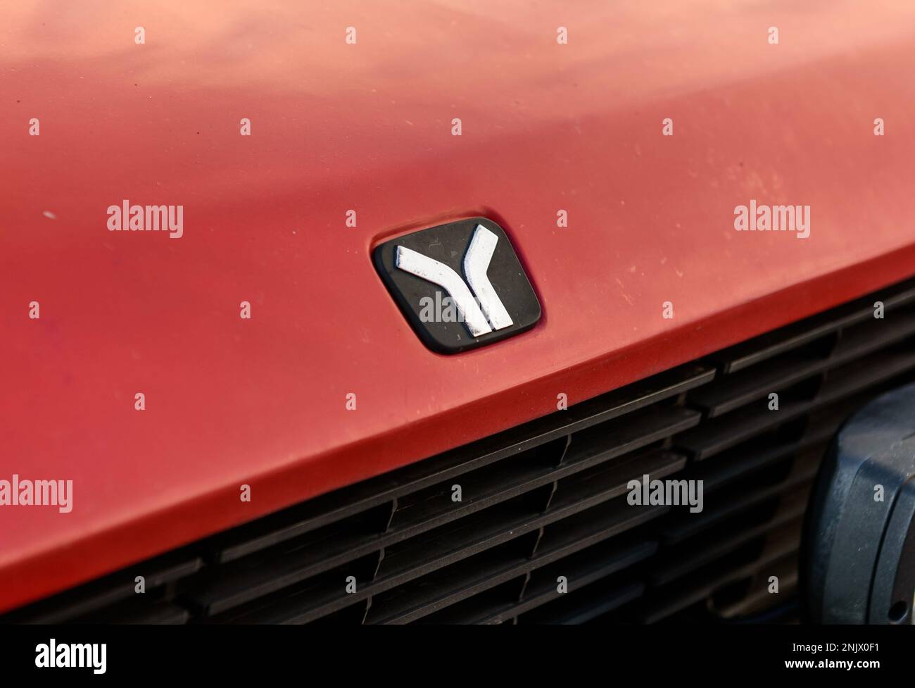 Close-up of Yugo logo on front hood of a red car Stock Photo
