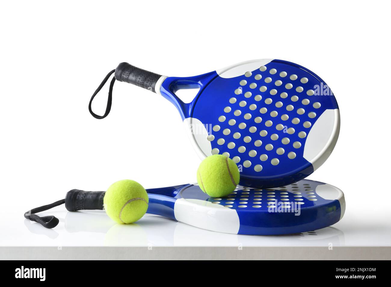 Set of paddle tennis rackets and balls the reflected on white table and white isolated background. Front view. Stock Photo
